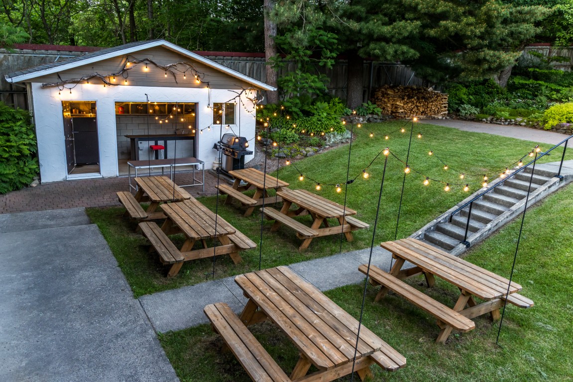 Tables à pique-nique multiples avec guirlandes lumineuses près du bâtiment BBQ à l'Espace du Carmel