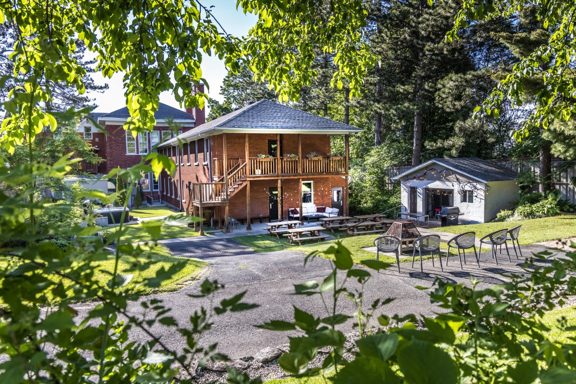 Bâtiment en brique avec terrasse couverte, tables à pique-nique et espace de feu à l'Espace du Carmel