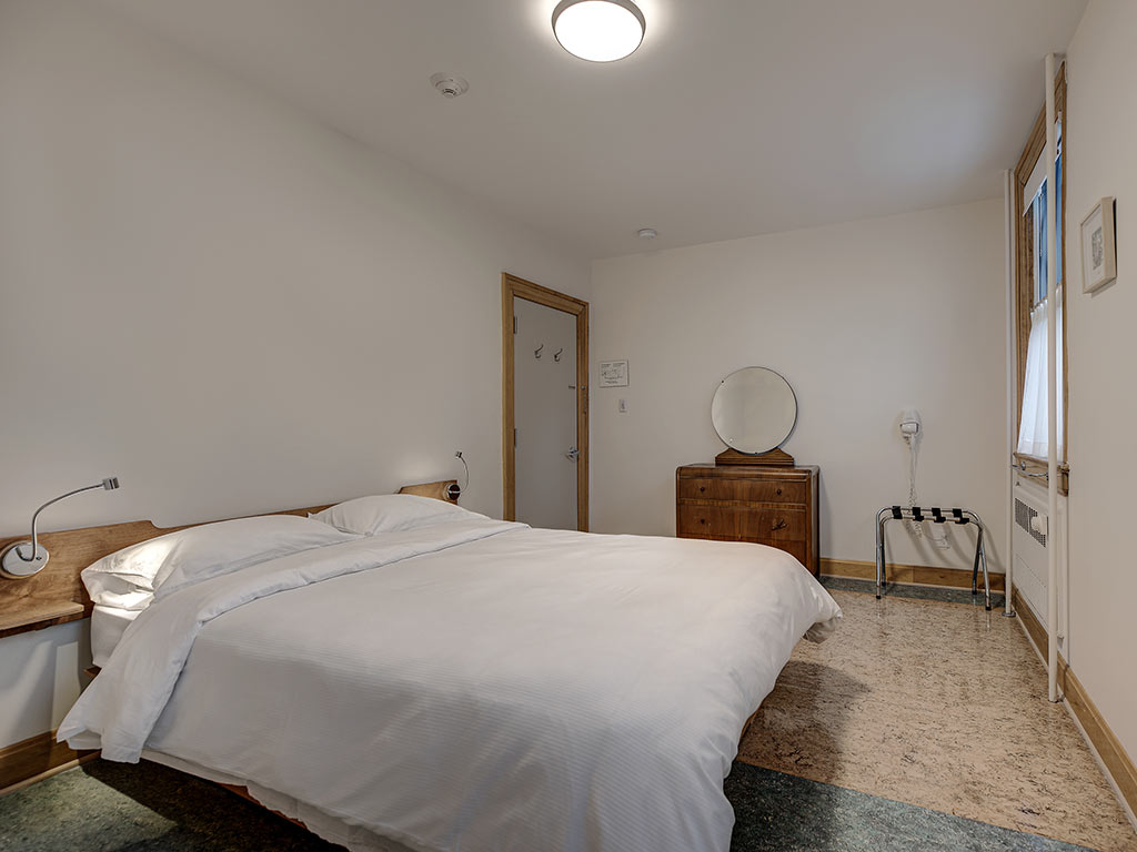 Chambre avec lit Queen, coiffeuse en bois et porte-bagages à l'Espace du Carmel