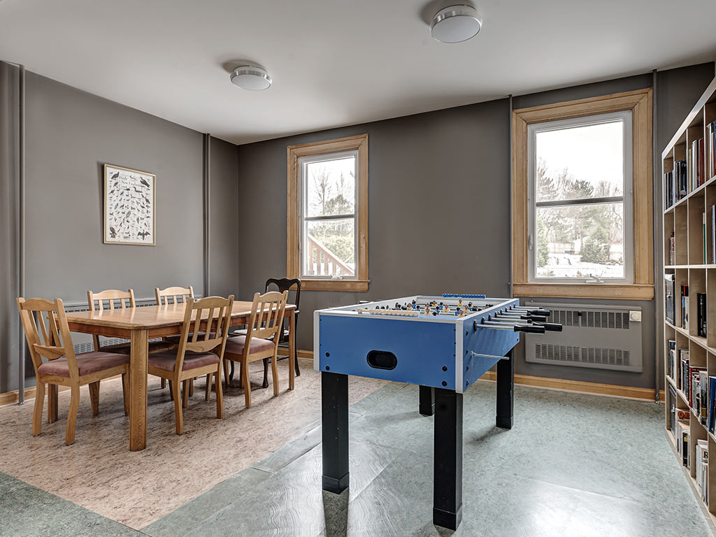 Salle de jeu avec table de baby-foot, coin repas et bibliothèque à l'Espace du Carmel