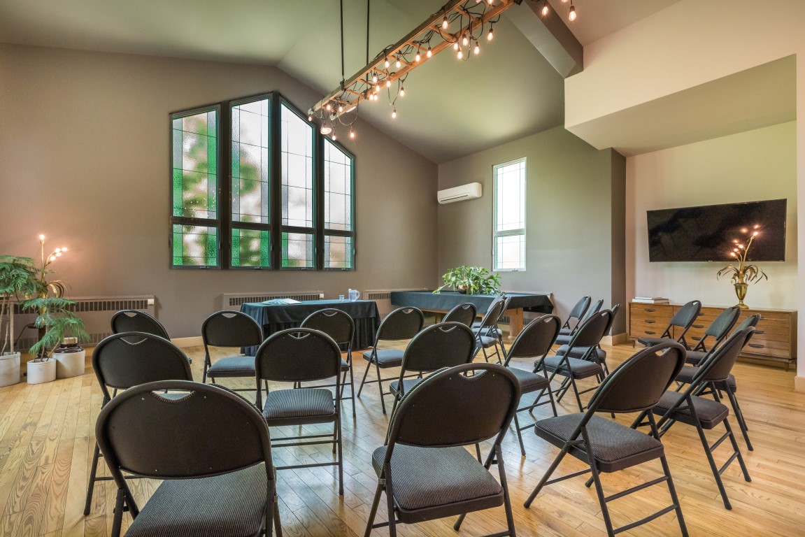 Salle de réunion aménagée en cercle avec fenêtres en vitrail patrimoniales à l'Espace du Carmel