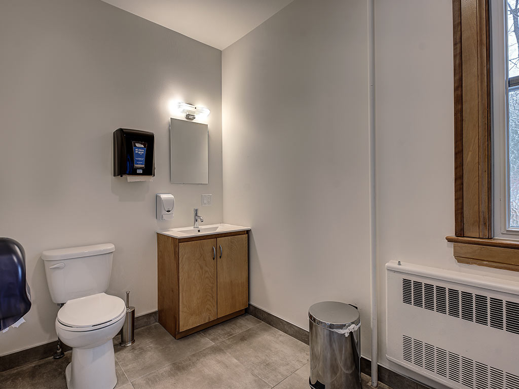 Salle de bain complète avec toilette, lavabo en bois et miroir à l'Espace du Carmel