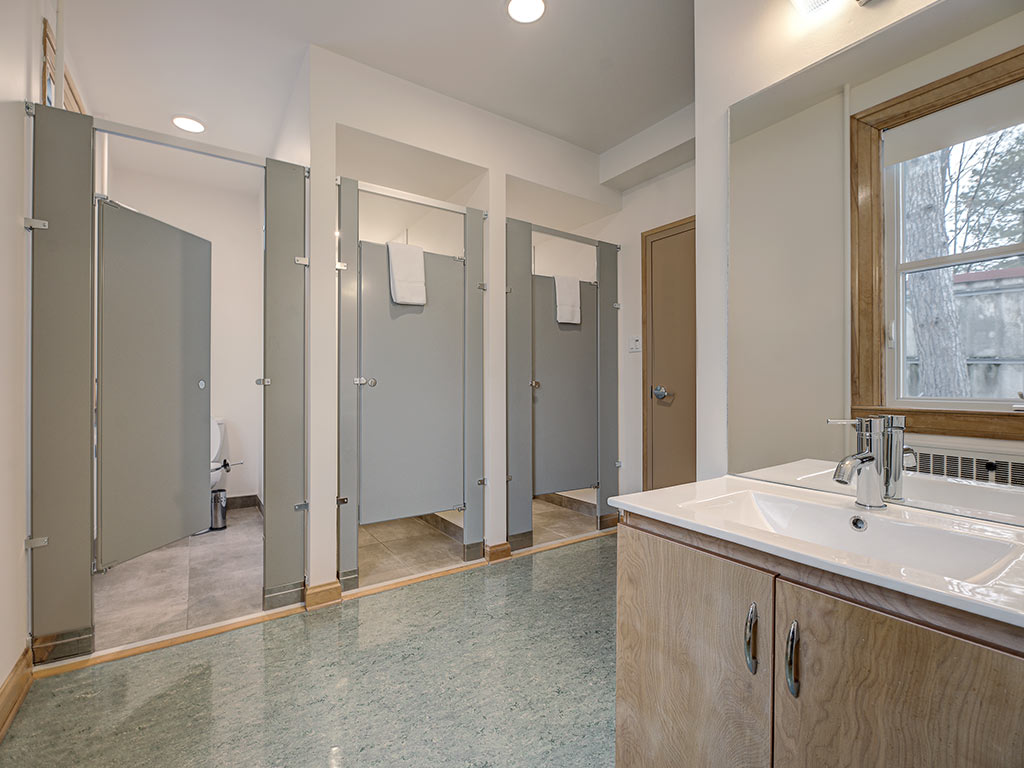 Vestiaire commun avec plusieurs douches individuelles et lavabo, aménagé pour les grands groupes à l'Espace du Carmel