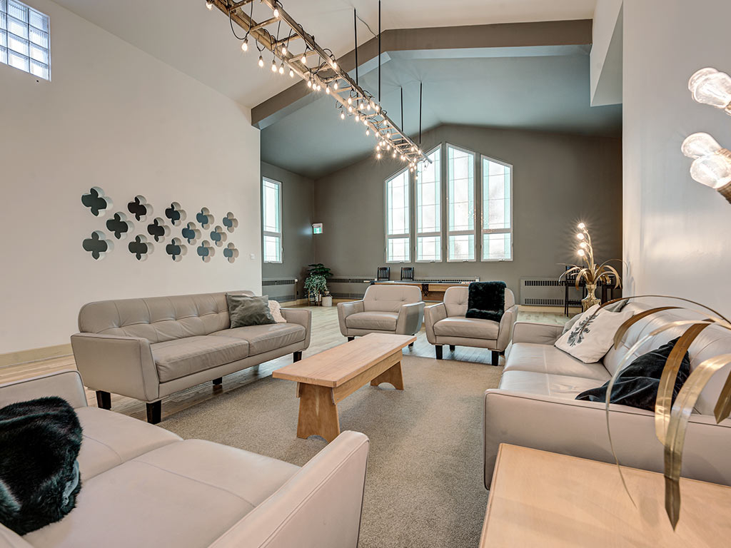 Grand salon lumineux avec plafond cathédrale, fenêtres à motifs et mobilier confortable à l'Espace du Carmel