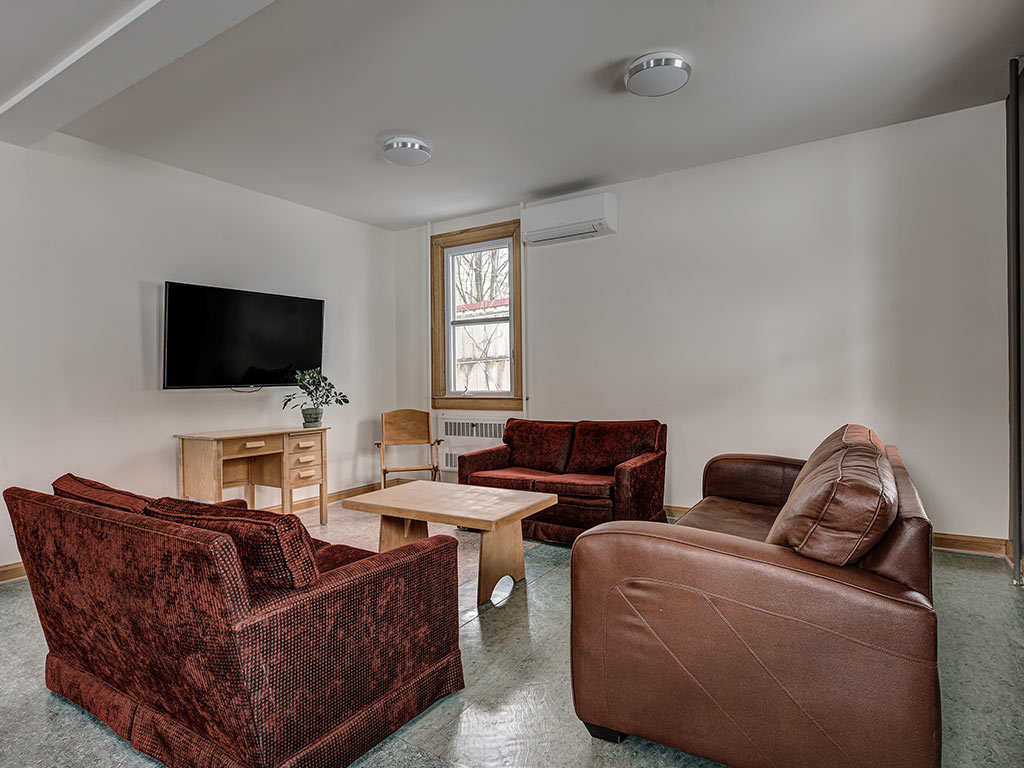 Salon avec canapés, fauteuils et télévision pour la détente en groupe à l'Espace du Carmel