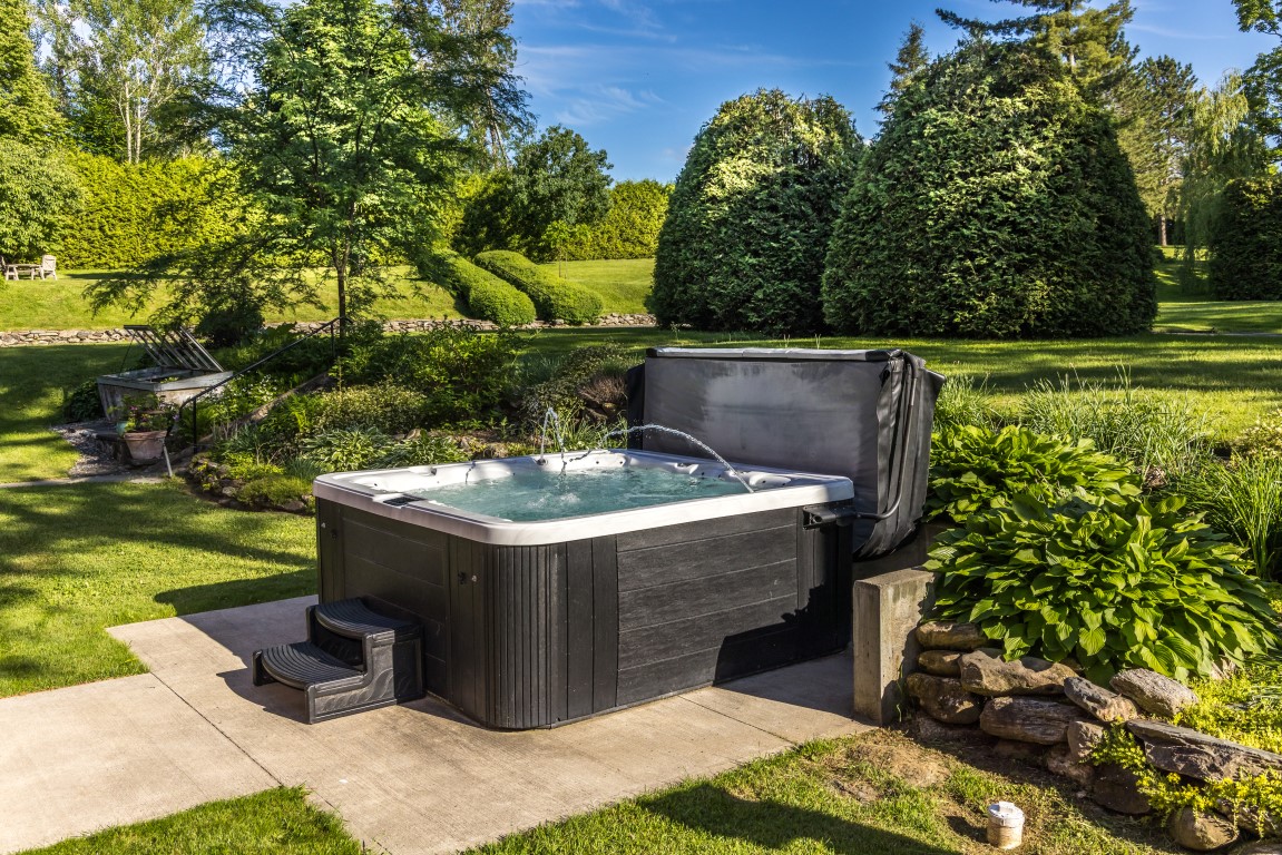 Spa privé extérieur entouré de verdure et d'arbustes taillés à l'Espace du Carmel
