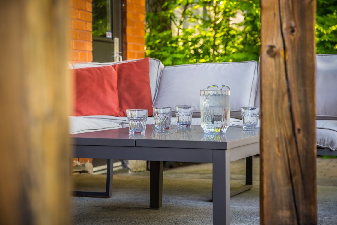 Coin lounge extérieur avec coussins et rafraîchissements sur une terrasse couverte à l'Espace du Carmel